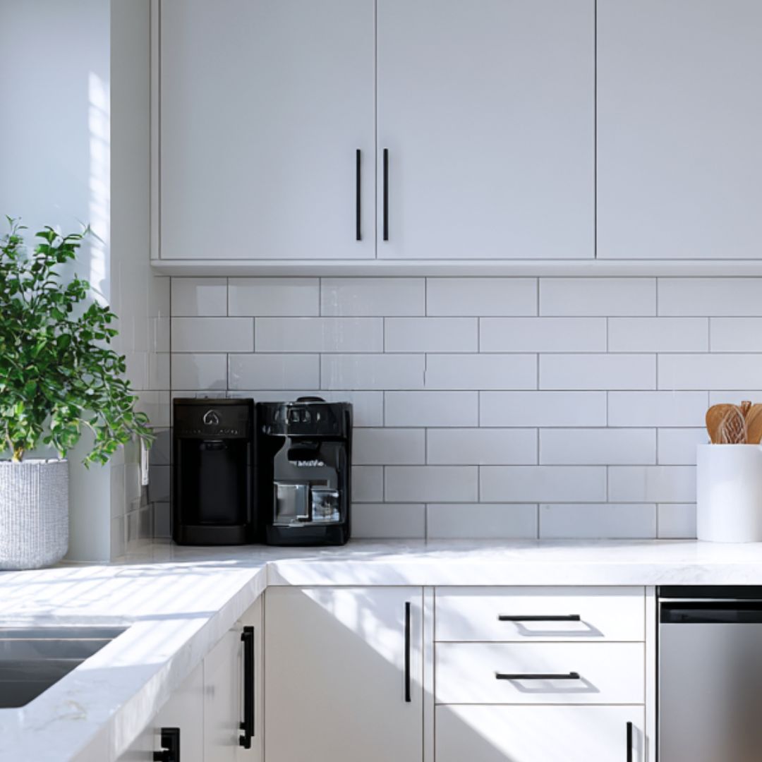 Modern kitchen with white cabinets, marble countertop, and coffee maker.